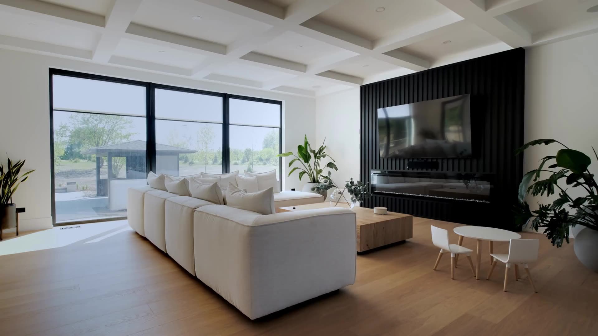 Bright modern living room with a white sectional, tall black-framed windows and a fireplace wall