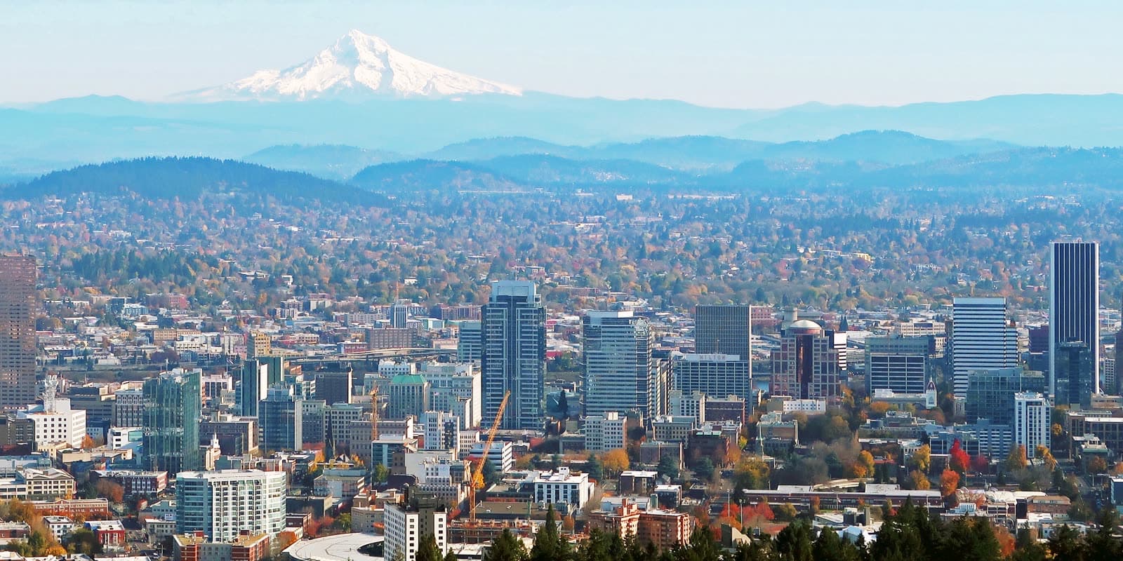 Downtown Portland and its neighborhoods spread below snowy Mount Hood, seen from Pittock Mansion.