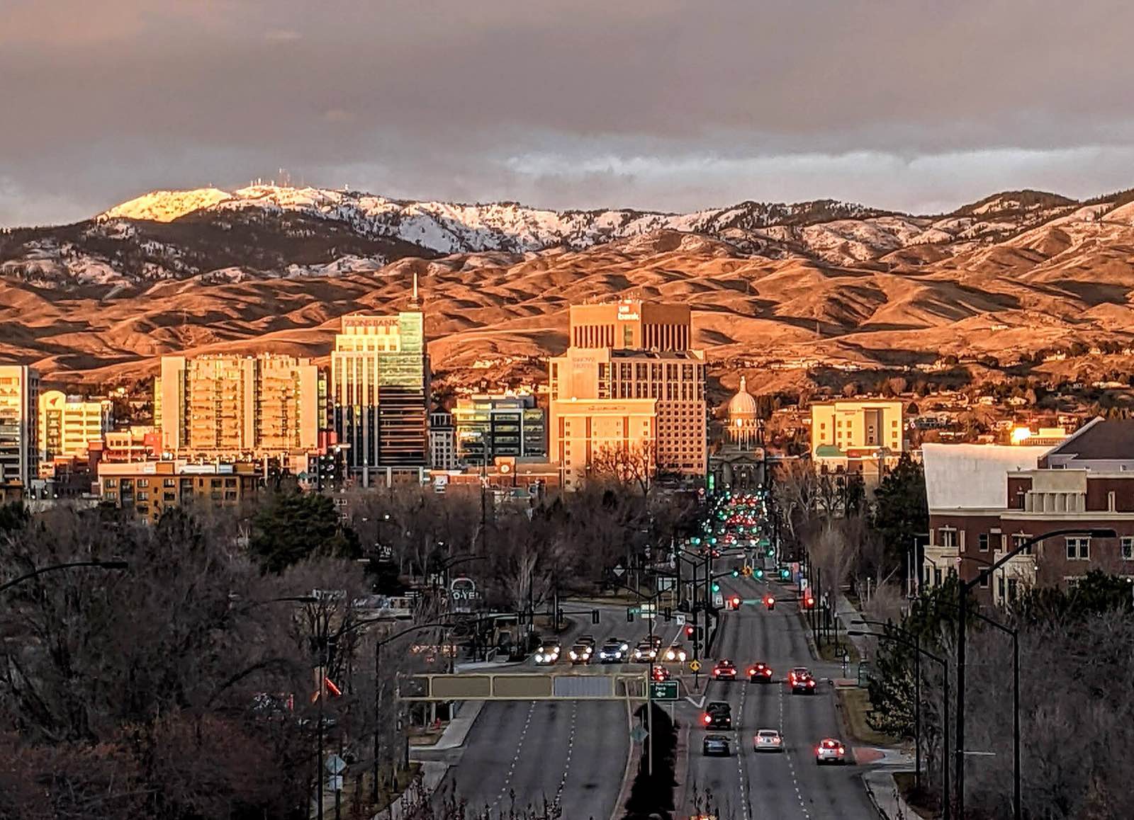 Downtown Boise glowing in late sun, with the snow-dusted Boise Foothills behind.