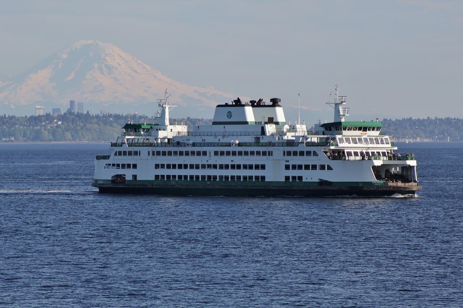 A Washington State ferry crossing Puget Sound with Mount Rainier and the Seattle skyline behind.