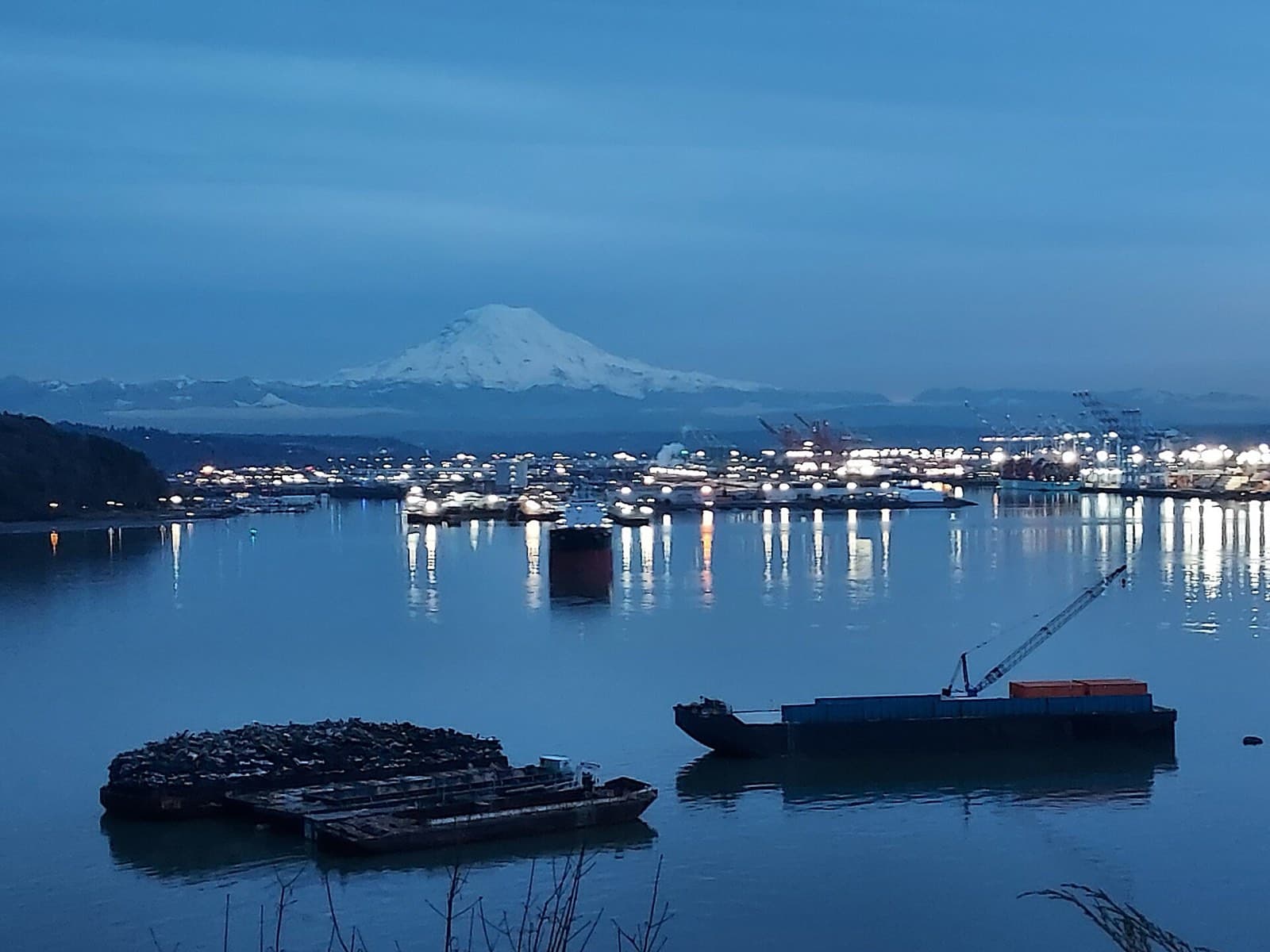 The lights of the Port of Tacoma on Commencement Bay at dusk, with Mount Rainier above.