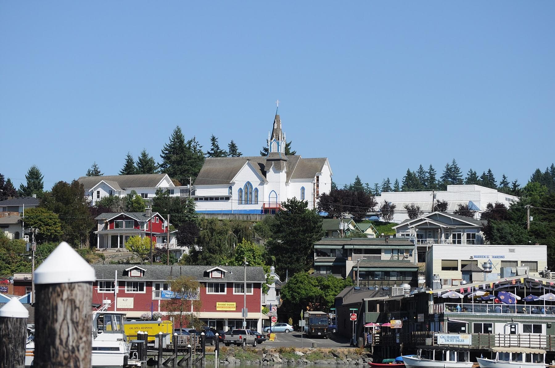 Downtown Poulsbo's waterfront buildings and white church steeple above Liberty Bay on a sunny day.